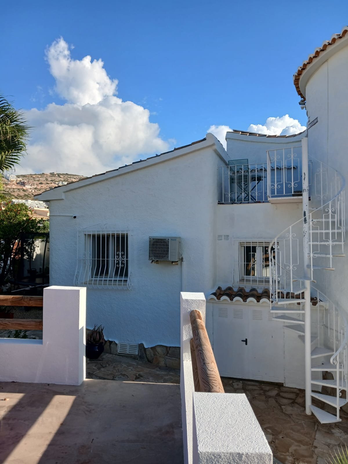 A white villa exterior with a spiral staircase, freshly painted