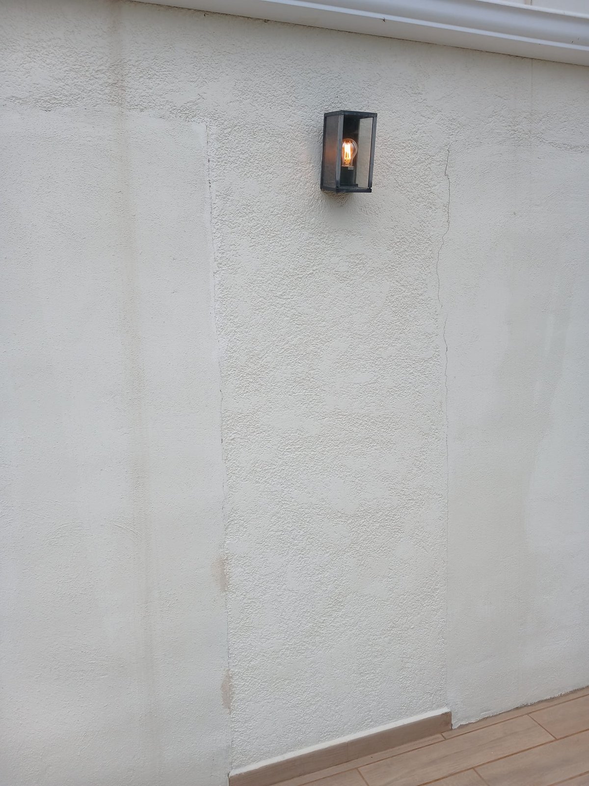 Close-up of a freshly painted white exterior wall with an outdoor lantern light