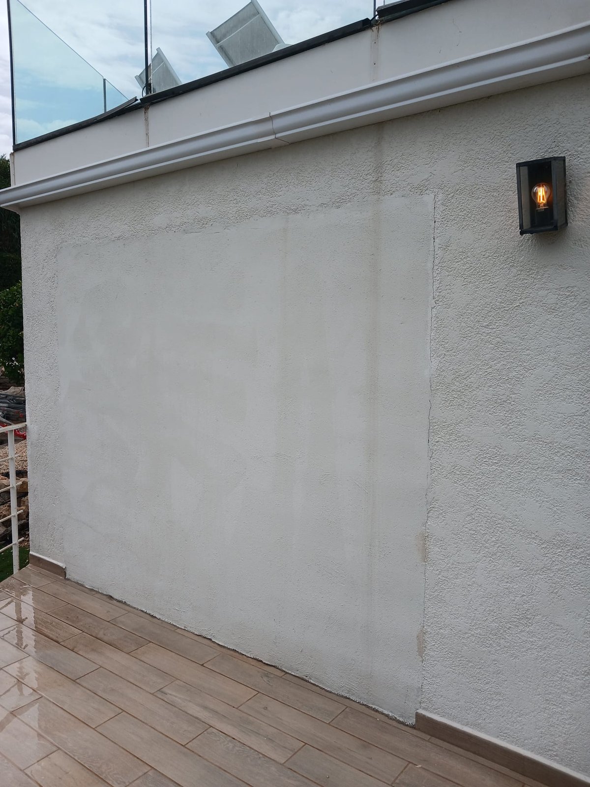 Close-up of a prepared exterior wall patch alongside the finished surrounding render