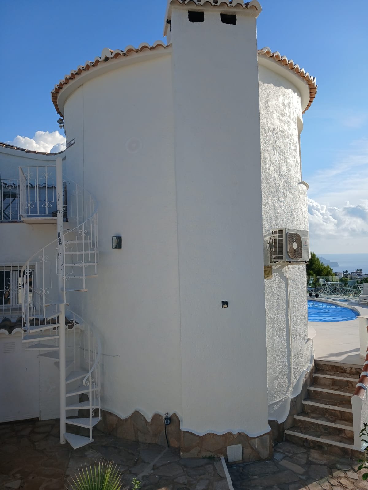 A curved exterior wall and chimney breast, part-finished in fresh white paint