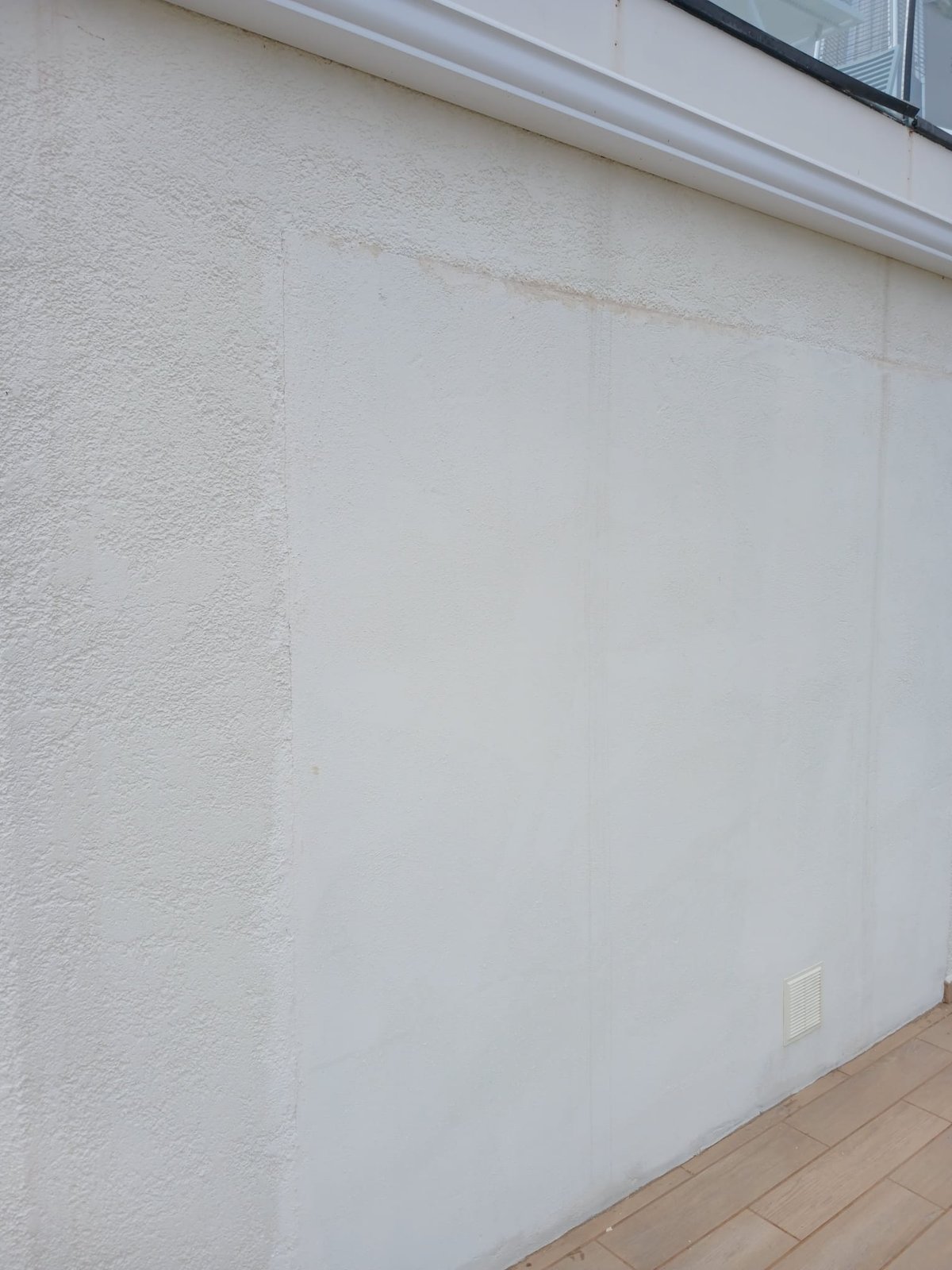 A section of exterior wall prepped and painted, blending seamlessly into the surrounding render